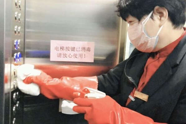 A person cleaning an elevator with a sign in Chinese. - Hongtai Hotel (Baofeng)