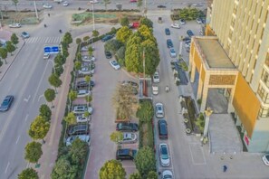 An aerial view of a parking lot with multiple rows of parked cars, a pedestrian walkway, and a building with a distinctive architectural design. - Hongtai Hotel (Baofeng)