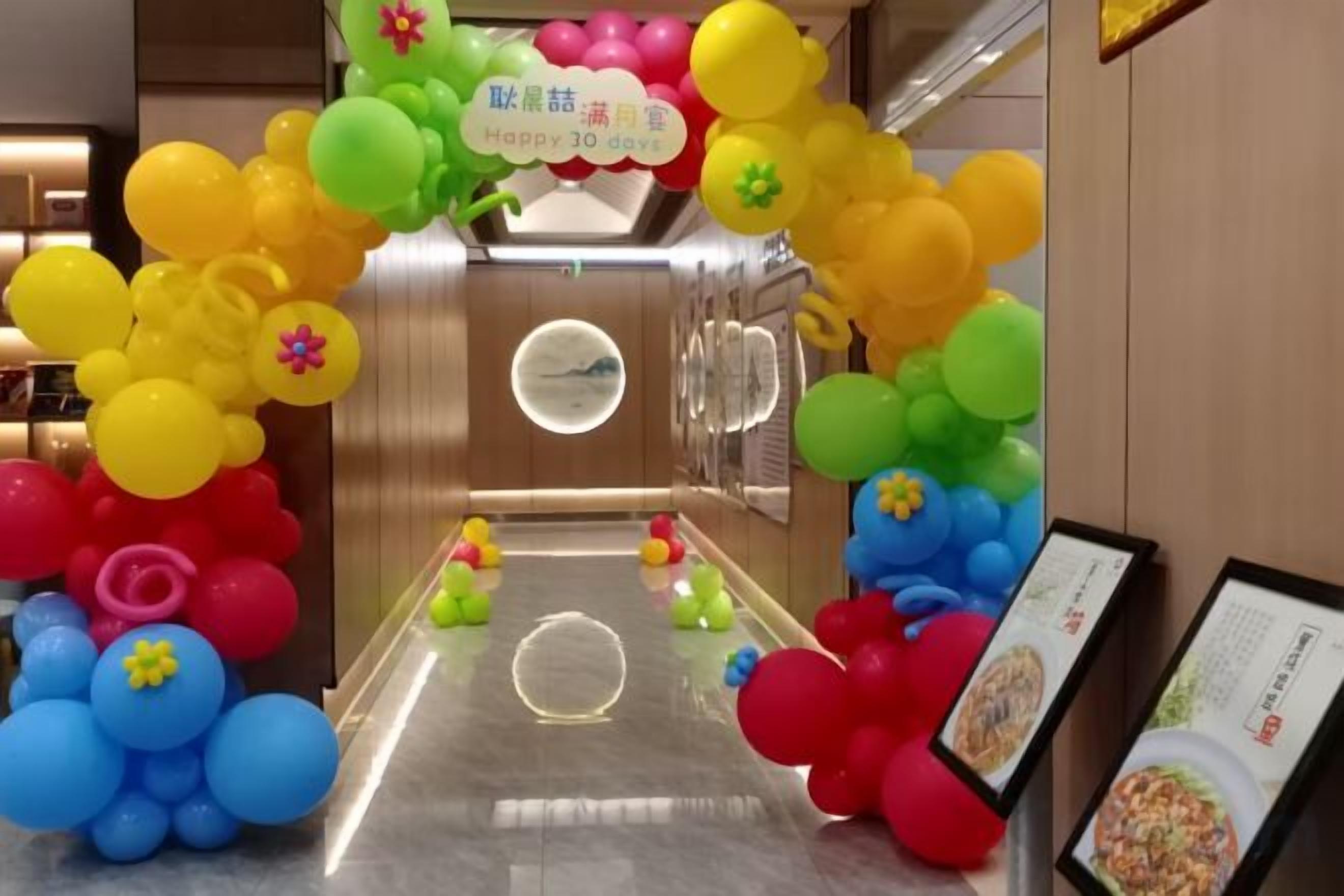 A hotel lobby with a colorful balloon arch and a central circular light fixture.