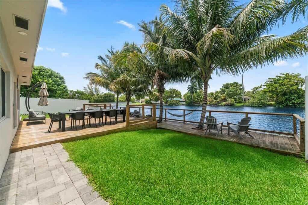 Une terrasse avec des meubles d’extérieur, une piscine et des palmiers.