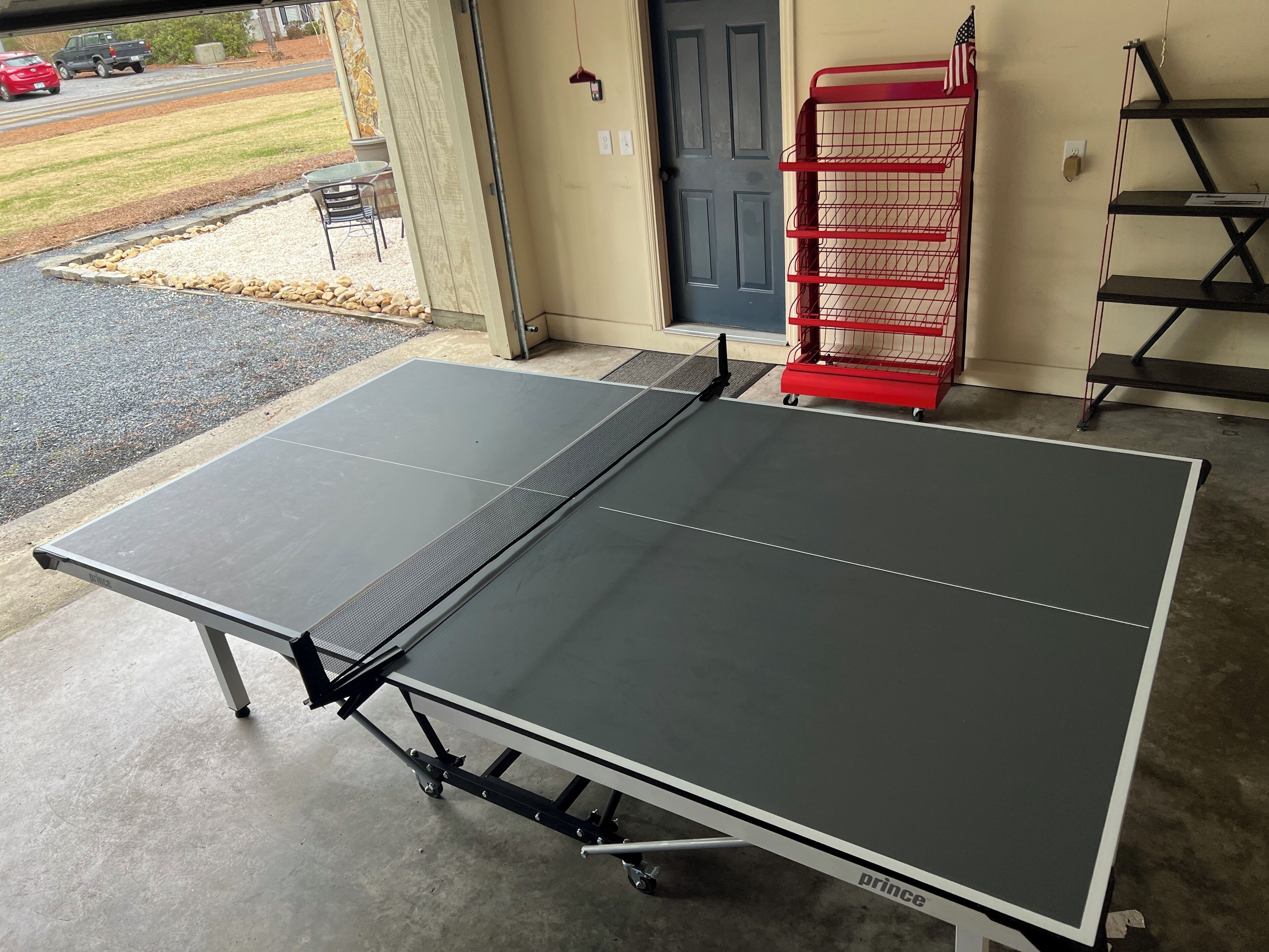 A ping pong table with wheels in a garage.