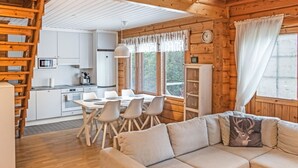 A cozy cabin interior with a dining area, kitchen, and a living room with a sofa and a round coffee table.