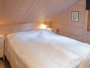 A bedroom with a wooden ceiling, a bed, a nightstand, and a wall-mounted lamp. - Vuokatin molle by Interhome (Sotkamo)