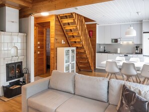 Interior moderno com escada de madeira, lareira, sala de jantar e cozinha.