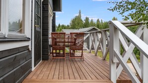 A wooden deck with a white railing, a table, and two chairs.