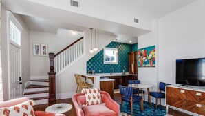 A living room with a staircase, a kitchen area, and a dining space. - High Style, Fun Decor, Awesome Location! 117D by Forsyth Park (Savannah)