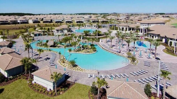 Ein Resort mit mehreren Swimmingpools, Palmen und Liegestühlen.