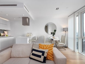Uma sala de estar moderna com sofá, mesa de jantar e área de cozinha.
