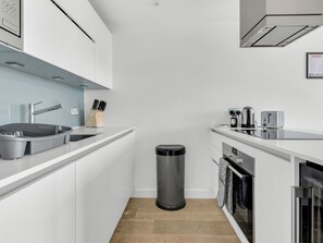 A modern kitchen with white cabinetry, a stainless steel sink, a coffee maker, and a toaster.