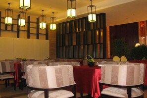 A hotel dining area with tables, chairs, and hanging lights. - Shuixi Hotel (Qianxi)