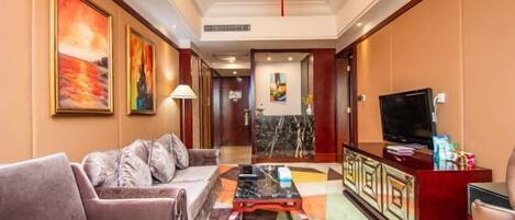 A hotel lobby with a sofa, coffee table, TV, and artwork on the walls.