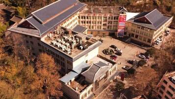 A multi-story building with a flat roof, a parking area, and a flag.