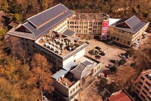 A large building with multiple floors, a parking area, and surrounding trees.