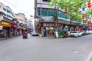 A street with shops and parked cars.