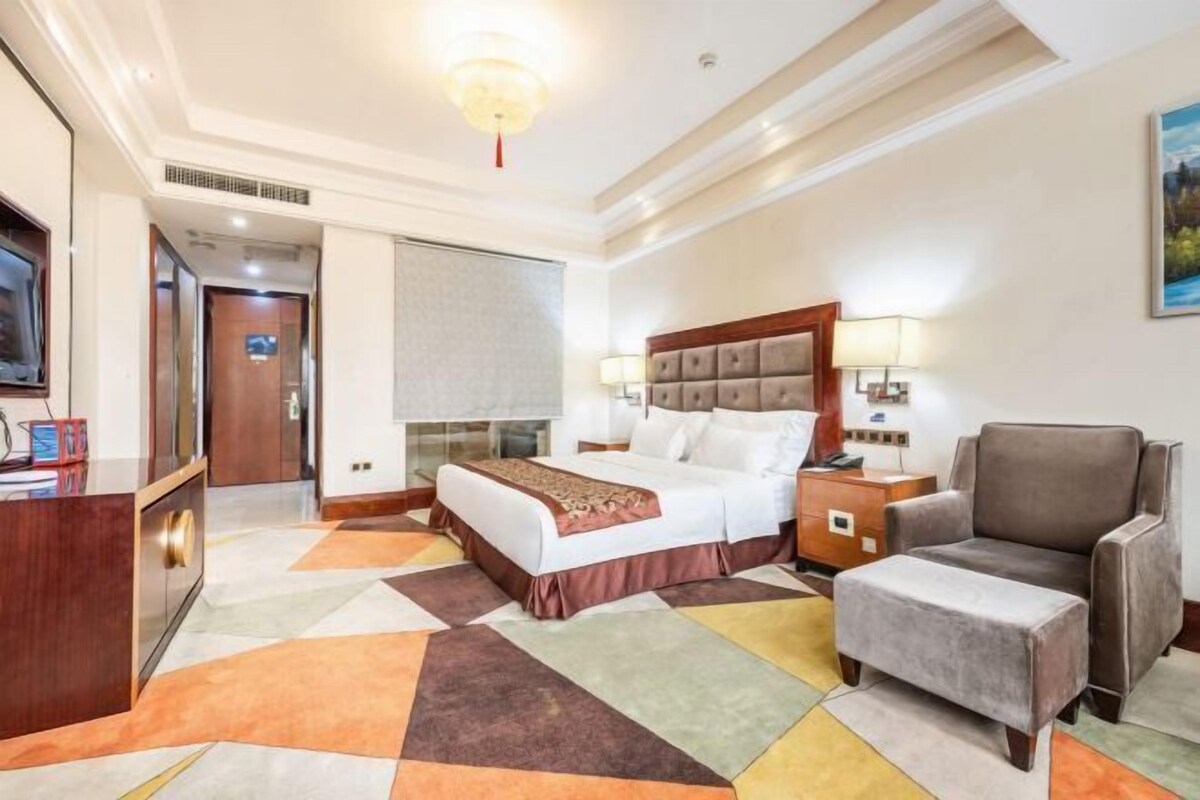 A hotel room with a bed, bedside table, chair, and a television.