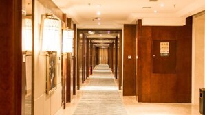 A hotel hallway with a marble floor, wooden doors, and framed artwork on the walls. - Shuixi Hotel (Qianxi)