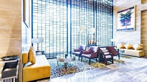 A modern lobby with a large window, a yellow sofa, a patterned rug, and a wall-mounted painting. - Shuixi Hotel (Qianxi)
