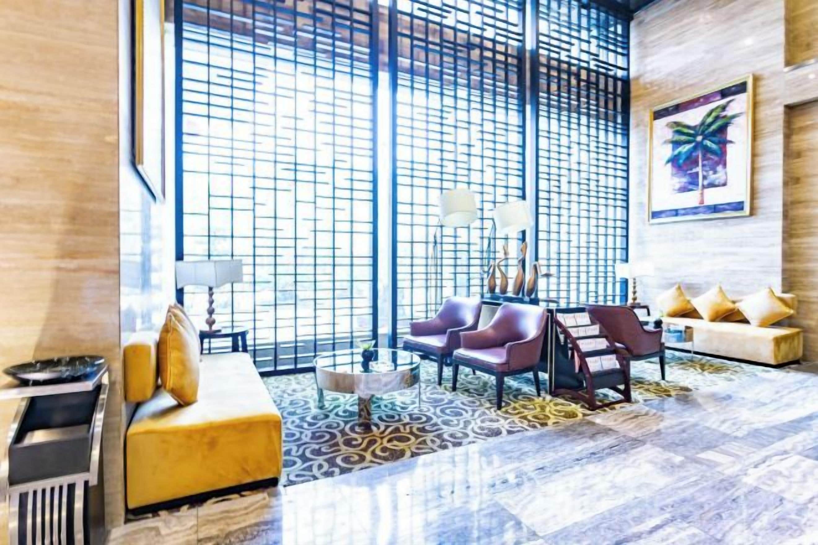 Un moderno vestíbulo de hotel con un gran ventanal, un sofá, sillas y una mesa de centro.