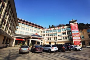A multi-story building with a parking lot in front. - Shuixi Hotel (Qianxi)