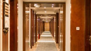 A hotel corridor with a marble floor, wooden doors, and a central light fixture. - Shuixi Hotel (Qianxi)