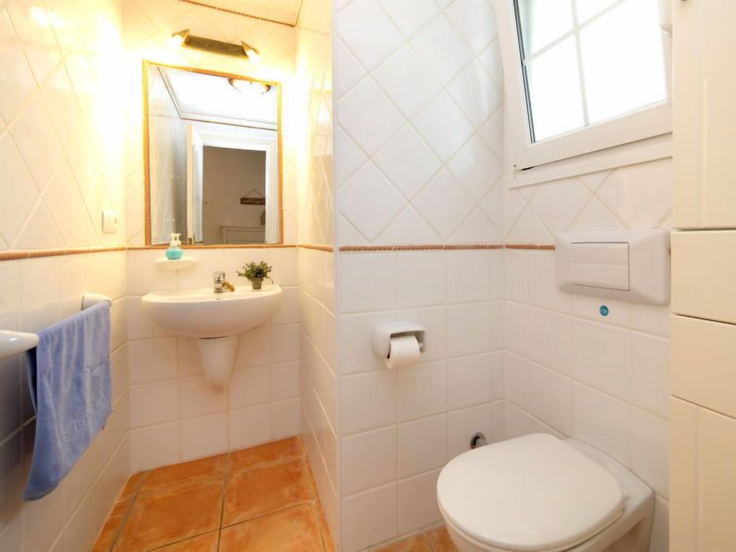Une salle de bain avec un lavabo, des toilettes et un miroir.