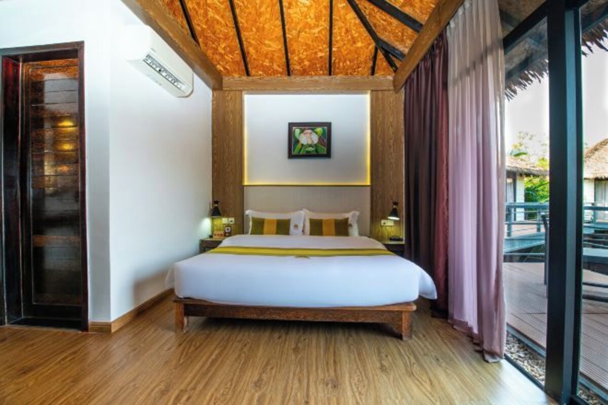 A bedroom with a wooden bed, a framed picture on the wall, and a view of the outside.