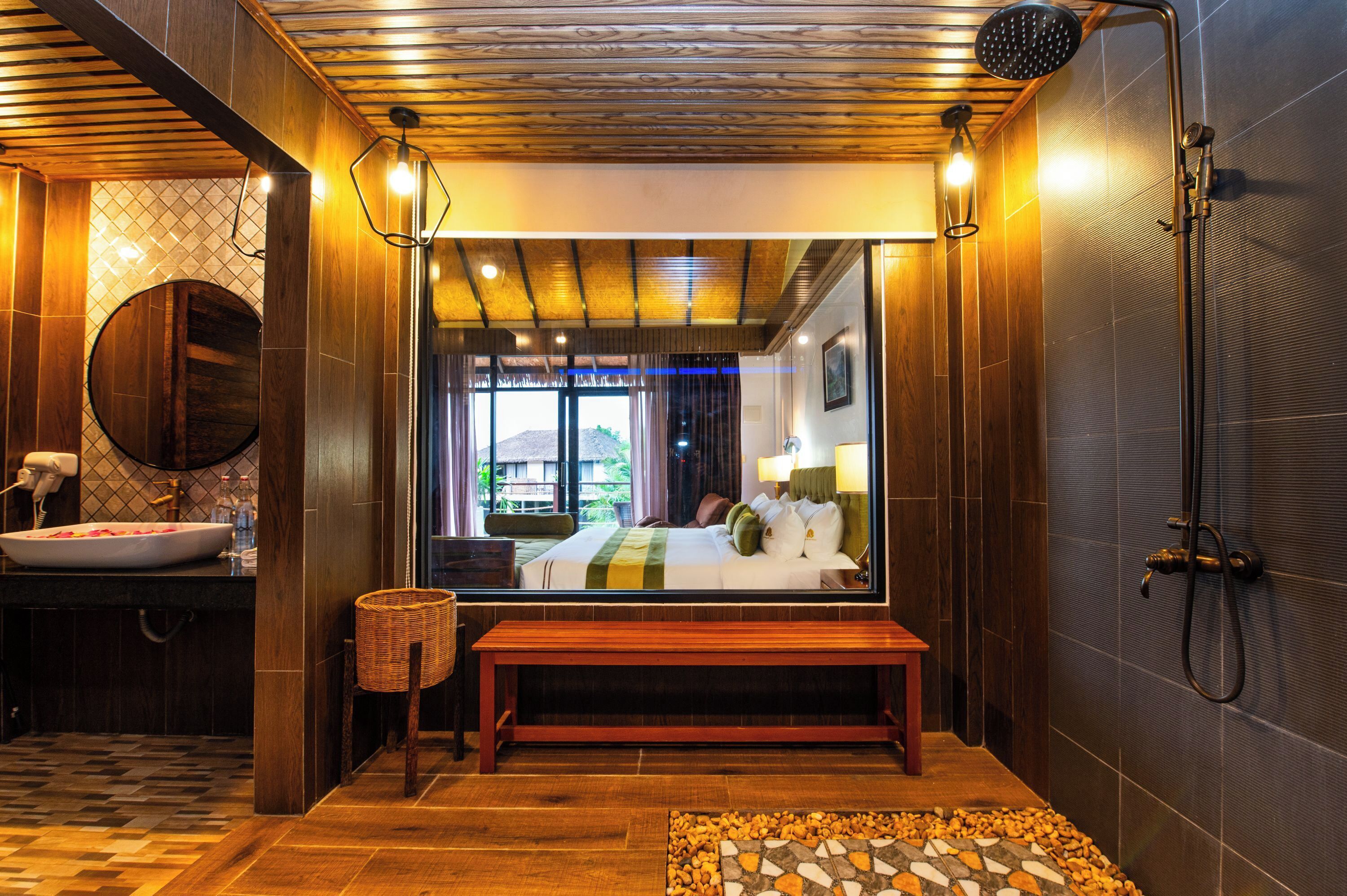 Een hotelbadkamer met een houten bankje, een grote spiegel, een douche en een wastafel.