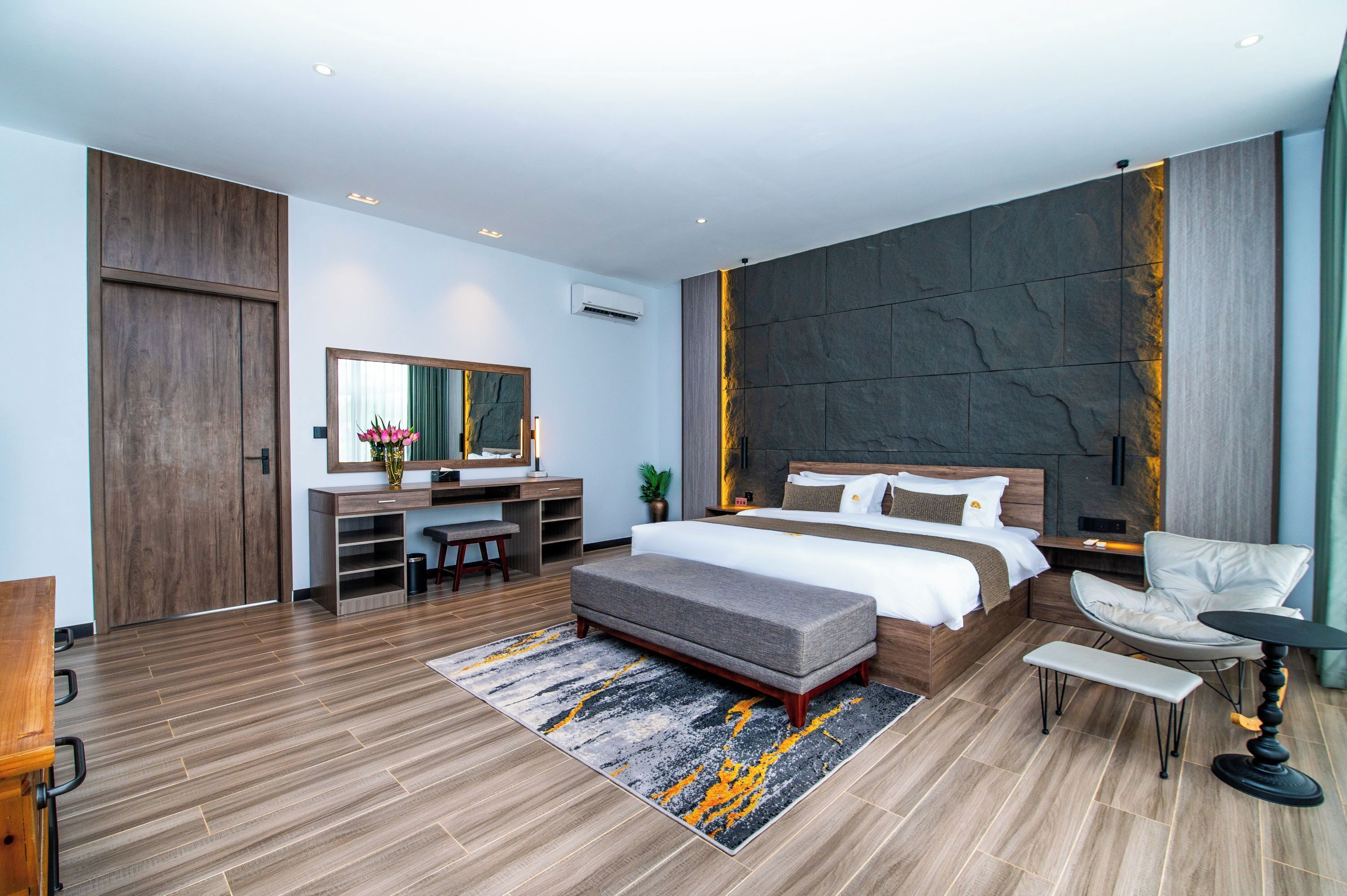 A modern bedroom with a large bed, a desk, and a chair.