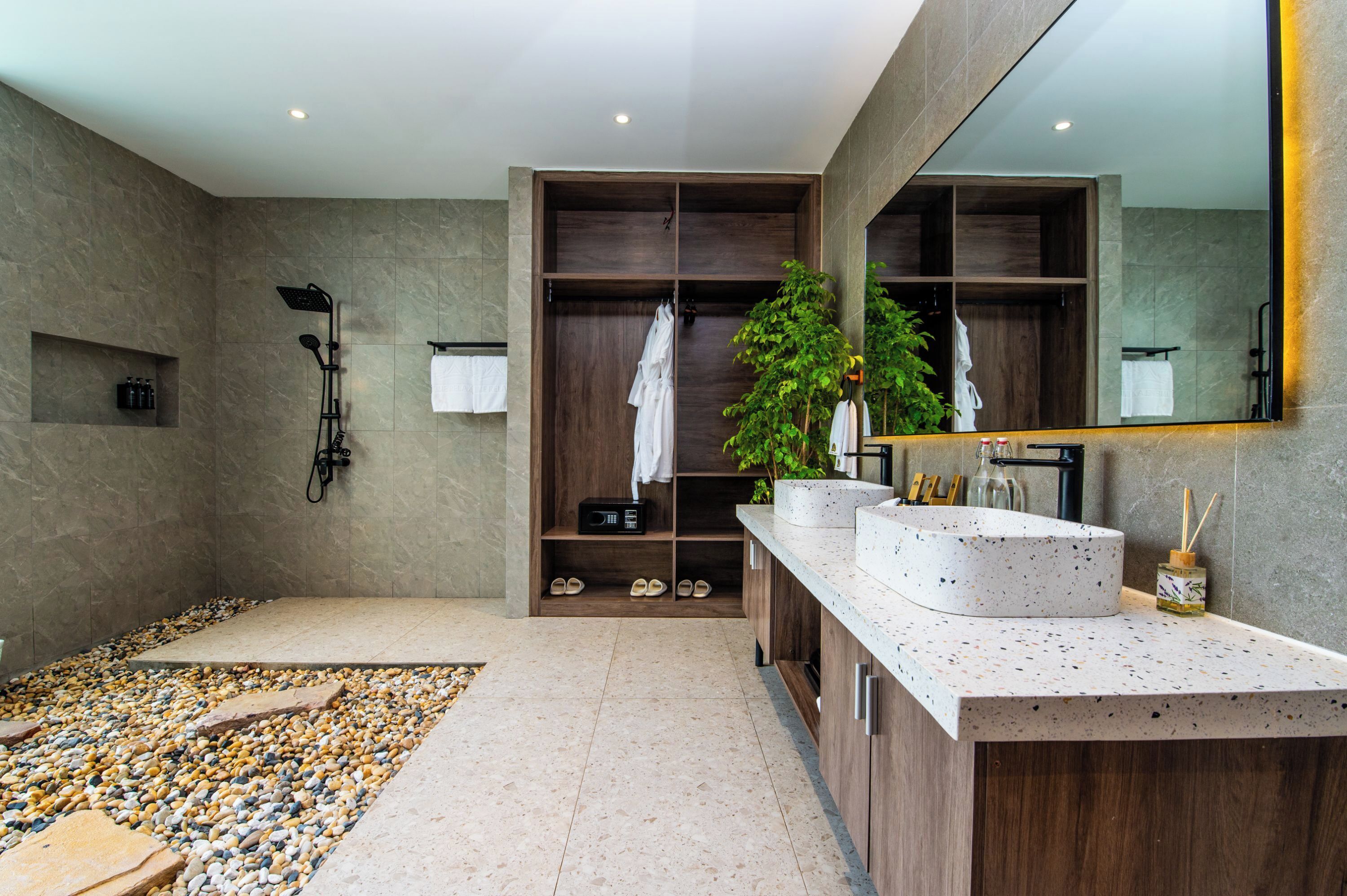 Un baño moderno con un espejo grande, ducha integrada y tocador con encimera de aspecto moteado.