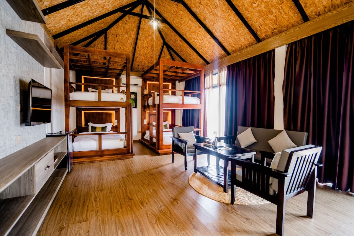 Une pièce spacieuse avec un plafond haut, des lits superposés en bois, un canapé et une table à manger.