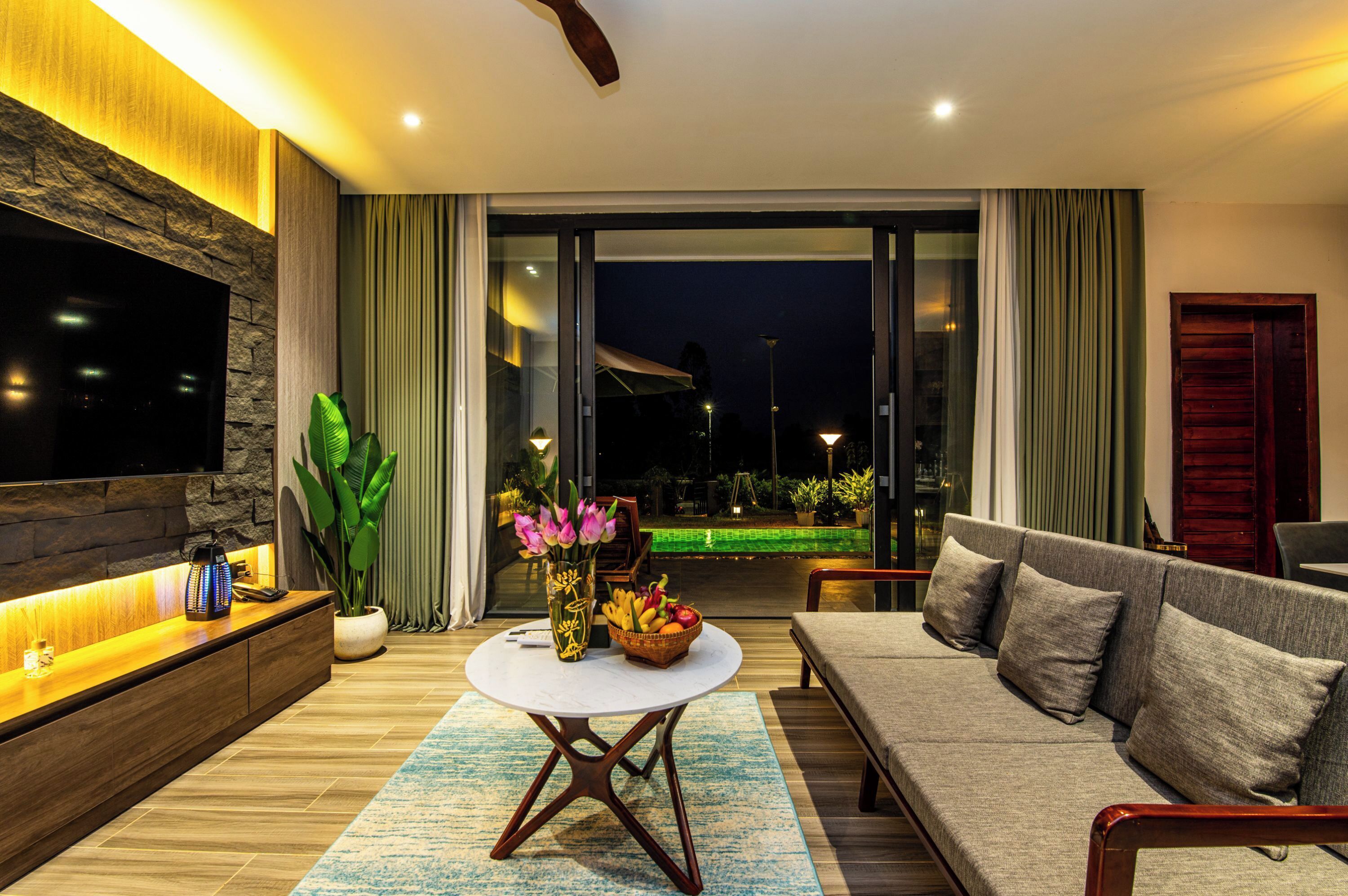 A modern living room with a sofa, a TV, a coffee table, and a potted plant.
