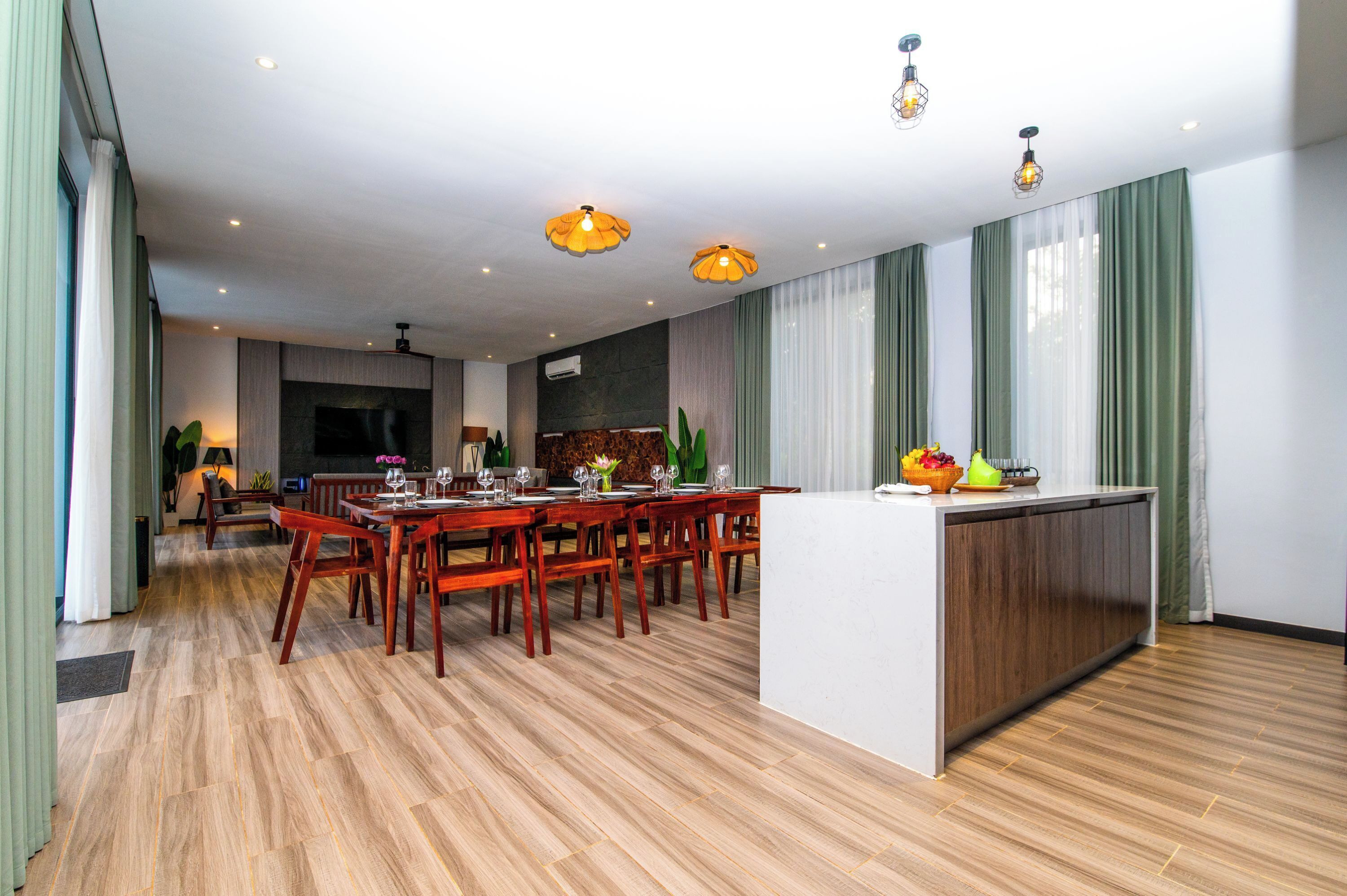 A modern hotel room with a dining area, wooden flooring, and a kitchen island.