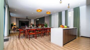 A modern hotel room with a dining area, wooden flooring, and a kitchen island.