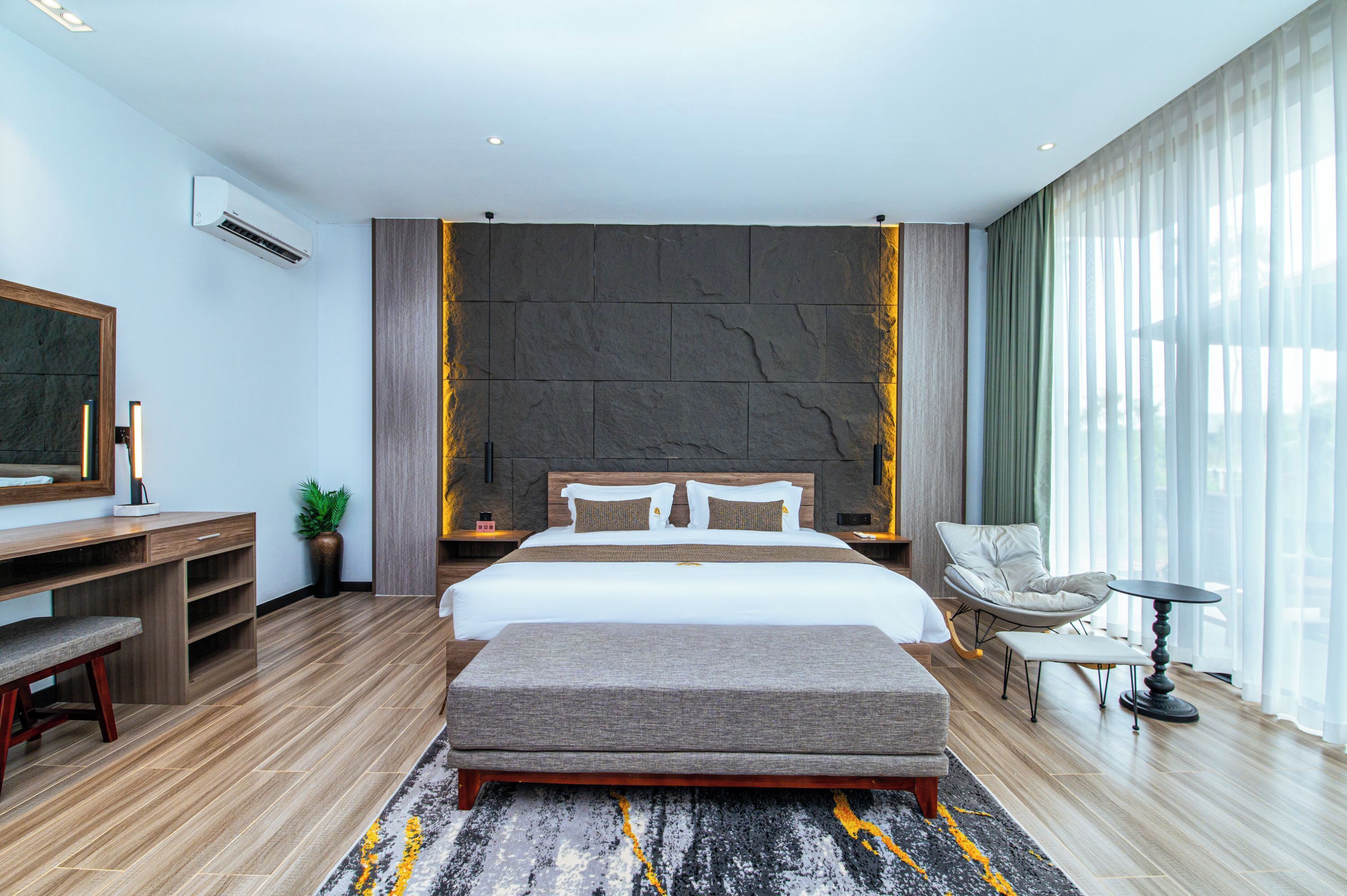 A modern hotel room with a large bed, a desk, a chair, and a TV.