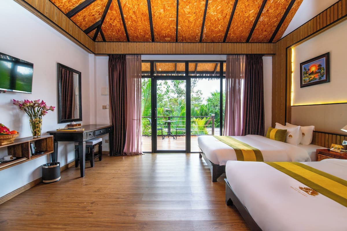 Une chambre d’hôtel avec un plafond en bois, un bureau avec une chaise, un lit avec une literie blanche, une télévision et une vue sur la verdure.