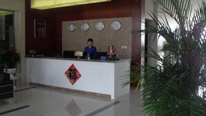 Een receptiebalie met een receptionist, een klok en een decoratief embleem.
