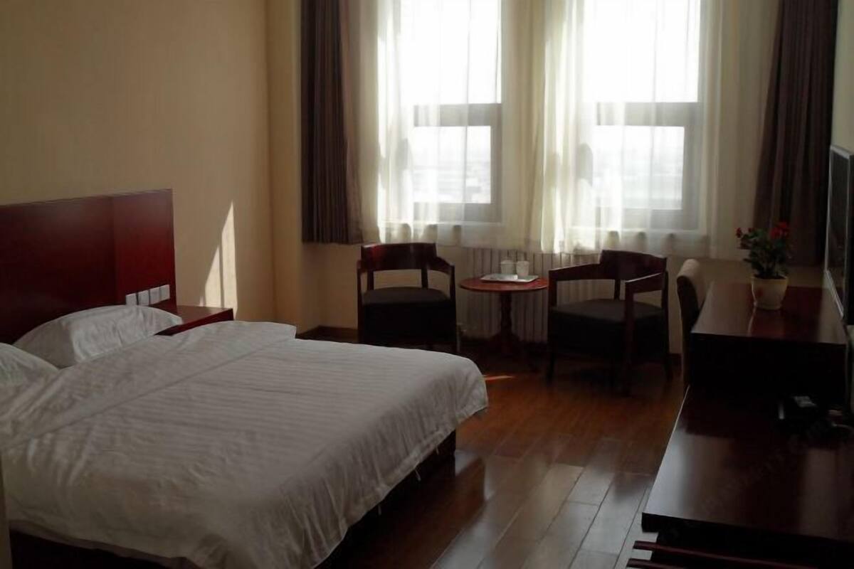 Une chambre d’hôtel avec un grand lit, un bureau, deux chaises et une petite table.