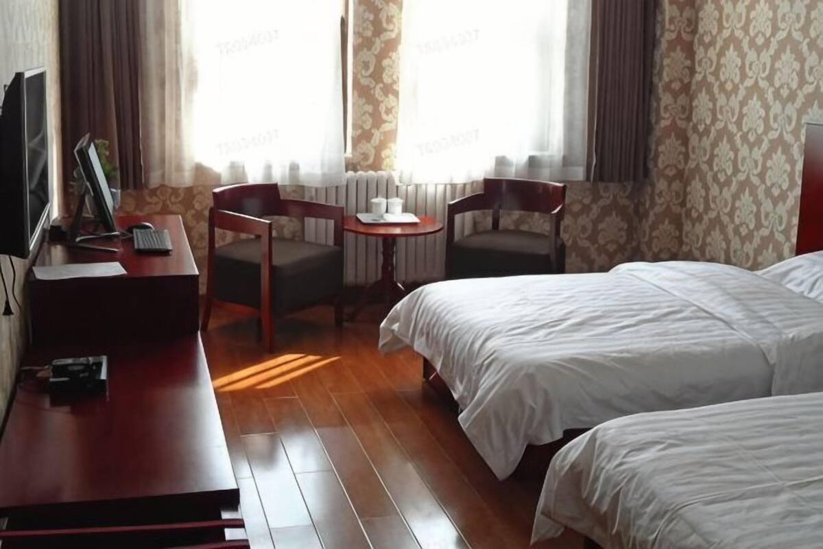 Une chambre d’hôtel avec deux lits, un bureau avec un ordinateur, une chaise et une petite table.
