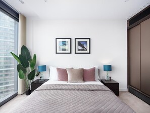 A modern hotel bedroom with a large bed, two bedside tables, a window with a view, and two framed pictures on the wall. - Lexicon, Angel by Interhome (London City)