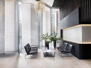 A modern reception area with glass walls, a black reception desk, and two black leather chairs. - Lexicon, Angel by Interhome (London City)