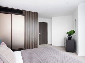 Une chambre à coucher moderne avec un lit, une armoire et une commode.