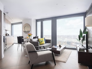A modern living room with a sofa, coffee table, and a dining area with chairs and a table.