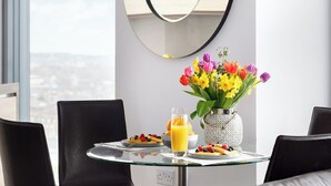 A dining table with breakfast items, a vase of flowers, and a city view. - Lexicon, Angel by Interhome (London City)