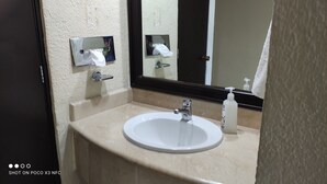 A bathroom with a white sink, a mirror, a towel dispenser, and a soap dispenser. - Bonito Estudio CON Vista Y Acceso AL MAR (Cancún)
