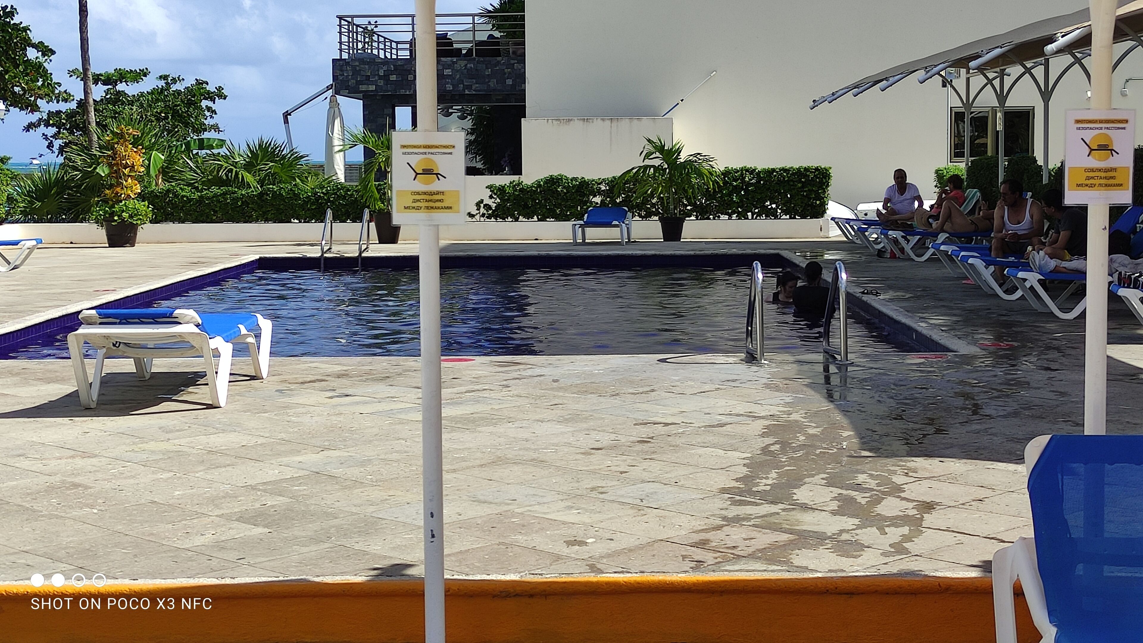 A swimming pool area with lounge chairs and a lifeguard stand.