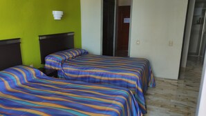 A hotel room with two beds, each with striped bedding, a green wall, and a white light fixture. - Bonito Estudio CON Vista Y Acceso AL MAR (Cancún)