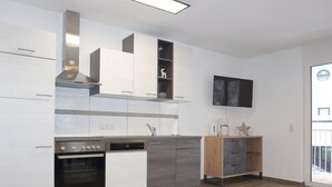 Eine moderne Küche mit weißen Schränken, einem eingebauten Backofen und einer Kaffeemaschine.