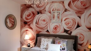 Ein Schlafzimmer mit einem großen Bett, einem Nachttisch mit Lampe und einer Wand mit floralem Wandbild.