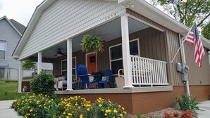 Ein Wohnhaus mit einer überdachten Veranda, einer Flagge und einem Garten mit gelben Blumen.