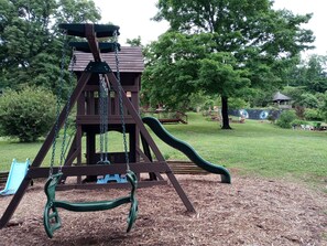 Playground with a swing set and slide set amidst a serene natural setting.